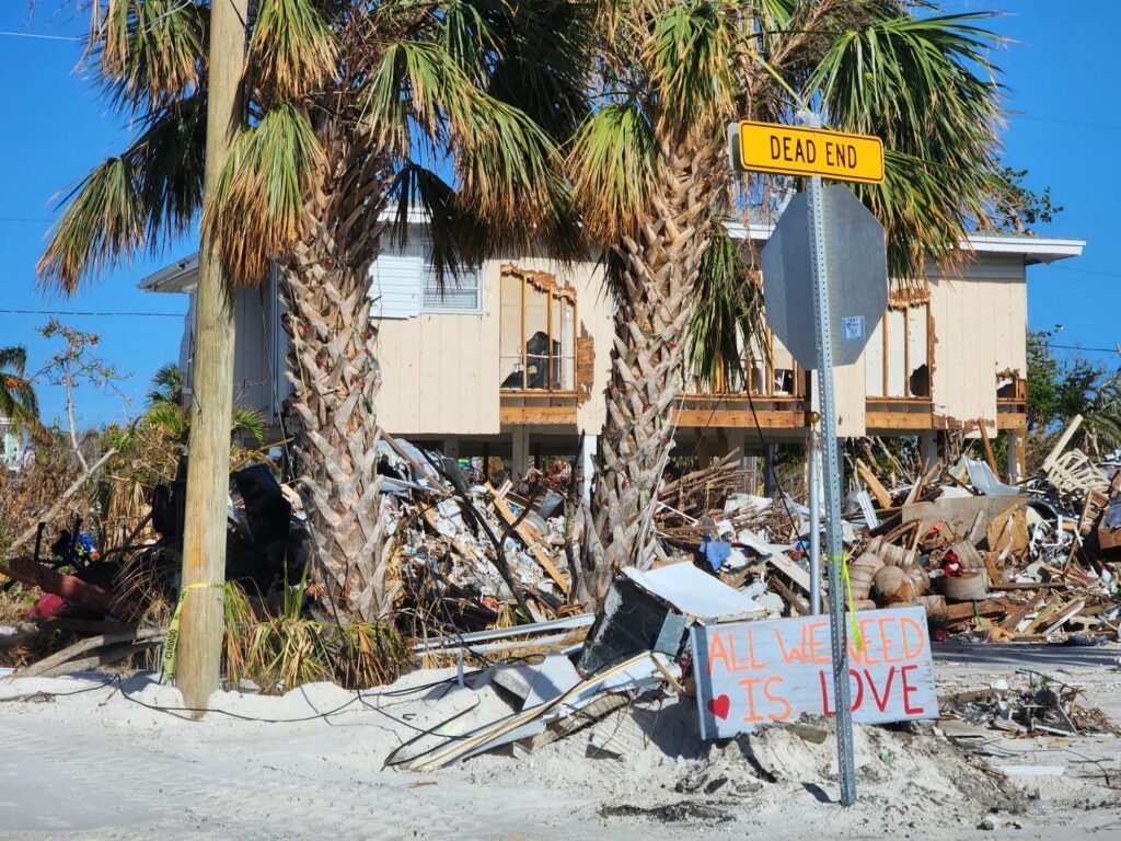 Hurricane-damaged Florida home with debris and downed palms